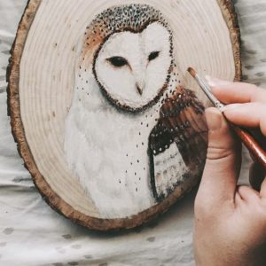 Художник рисует на древесине животных
